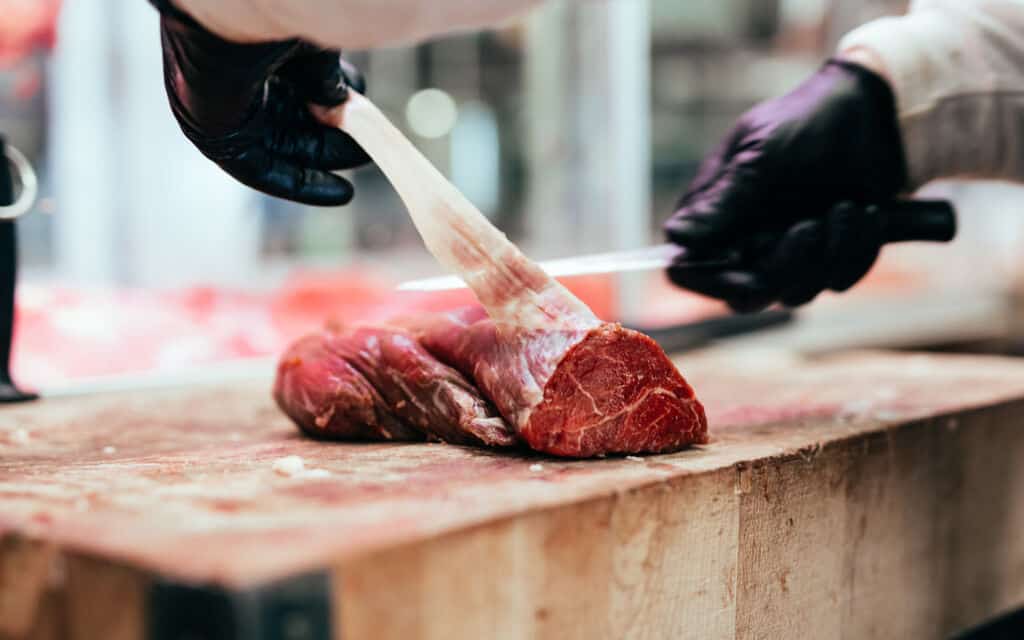 Butcher cutting meat at counter in butchery